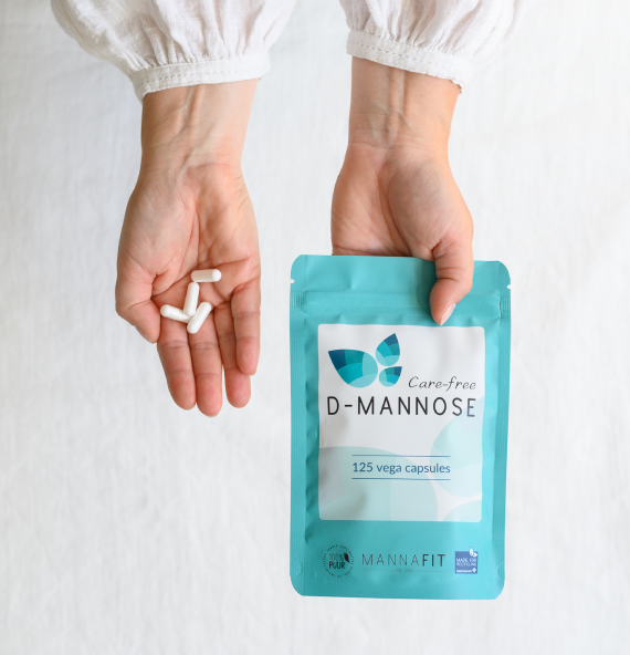MannaFit Care-free D-mannose zakje en hand met capsules